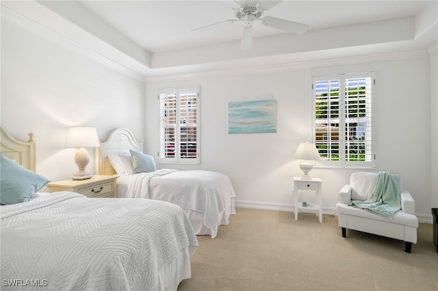 carpeted bedroom with baseboards, a ceiling fan, crown molding, and a tray ceiling