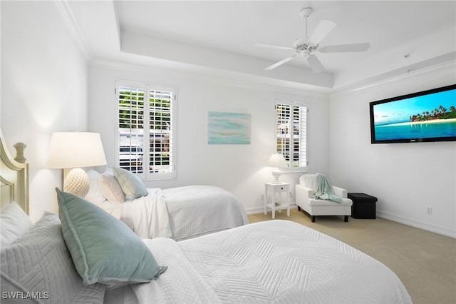 carpeted bedroom with baseboards, multiple windows, a tray ceiling, and ceiling fan