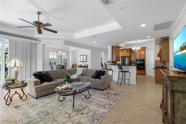 living area with visible vents, ceiling fan with notable chandelier, light tile patterned flooring, and a tray ceiling