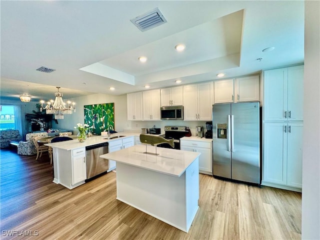 5445 Double Eagle Cir Unit 3012, Ave Maria, FL 34142 - kitchen with stainless steel appliances, a tray ceiling, a peninsula, light wood finished floors, and recessed lighting