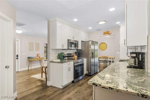 1424 SW 49th St, Cape Coral, FL 33914 - kitchen featuring stainless steel appliances, wood finished floors, white cabinetry, light stone countertops, and recessed lighting