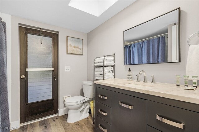 1424 SW 49th St, Cape Coral, FL 33914 - full bath with vanity, wood finished floors, toilet, and a skylight