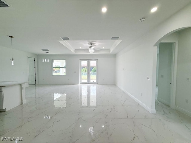 2703 42nd St SW, Lehigh Acres, FL 33976 - empty room with arched walkways, light marble finish floors, ceiling fan, a tray ceiling, and baseboards