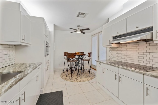 2000 Royal Marco Way Unit 607, Marco Island, FL 34145 - kitchen with under cabinet range hood, black electric stovetop, stainless steel oven, light tile patterned flooring, and ceiling fan