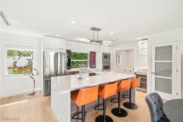 360 10th Ave S Unit B200, Naples, FL 34102 - kitchen featuring wine cooler, modern cabinets, white cabinetry, light wood-style flooring, and appliances with stainless steel finishes