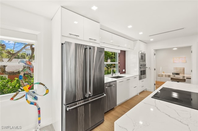 360 10th Ave S Unit B200, Naples, FL 34102 - kitchen featuring modern cabinets, white cabinetry, light stone counters, a sink, and appliances with stainless steel finishes