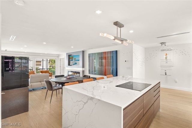 360 10th Ave S Unit B200, Naples, FL 34102 - kitchen with a glass covered fireplace, open floor plan, modern cabinets, black electric stovetop, and light wood-style flooring