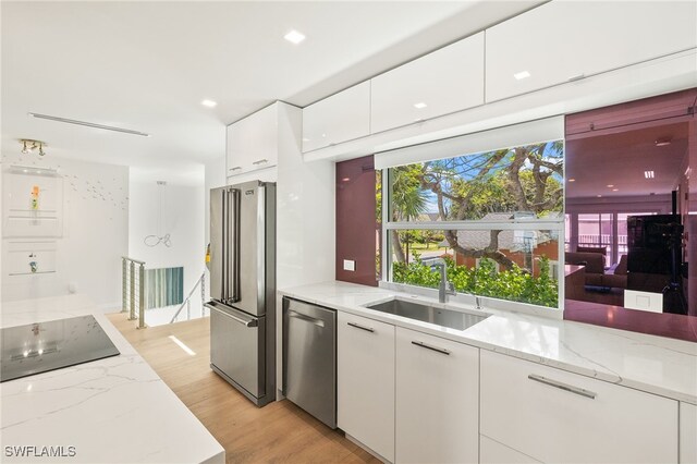 360 10th Ave S Unit B200, Naples, FL 34102 - kitchen featuring light stone countertops, light wood-style floors, white cabinetry, a sink, and stainless steel appliances