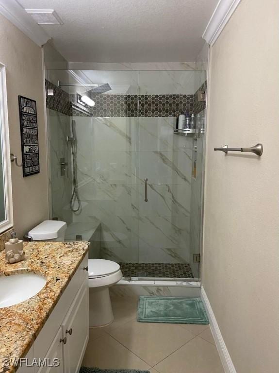 full bathroom featuring vanity, toilet, a marble finish shower, tile patterned floors, and baseboards