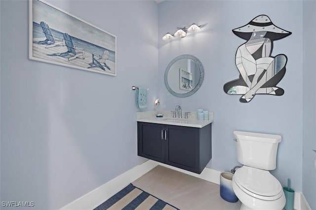 bathroom featuring baseboards, vanity, and toilet
