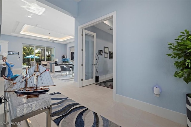 hall featuring baseboards and a tray ceiling