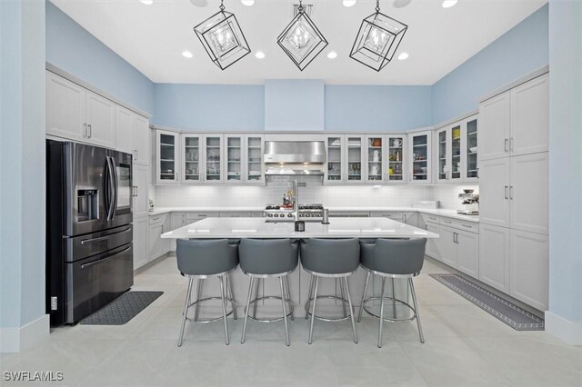 kitchen featuring a kitchen breakfast bar, extractor fan, stainless steel fridge, light countertops, and tasteful backsplash