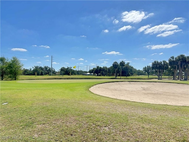 surrounding community featuring golf course view and a yard