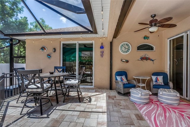 view of patio with ceiling fan and glass enclosure