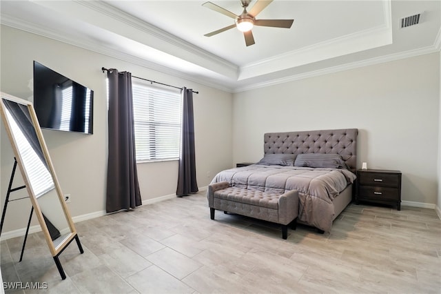 bedroom with a tray ceiling, visible vents, baseboards, and ornamental molding