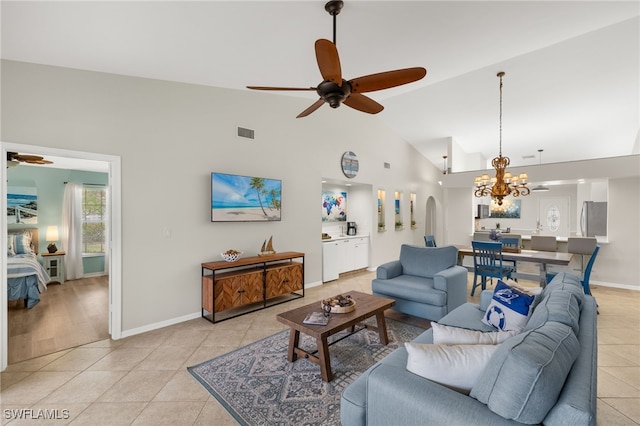 living area featuring light tile patterned floors, high vaulted ceiling, ceiling fan with notable chandelier, and visible vents