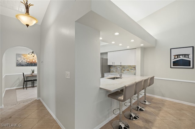 interior space featuring baseboards, recessed lighting, arched walkways, a sink, and light tile patterned floors