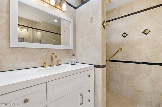 full bathroom featuring vanity, tiled shower, and tile walls