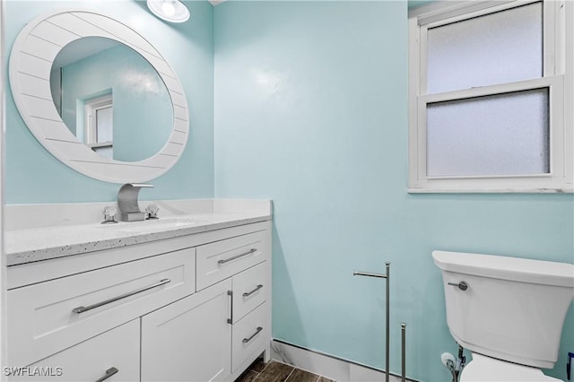 bathroom with toilet, wood finished floors, and vanity