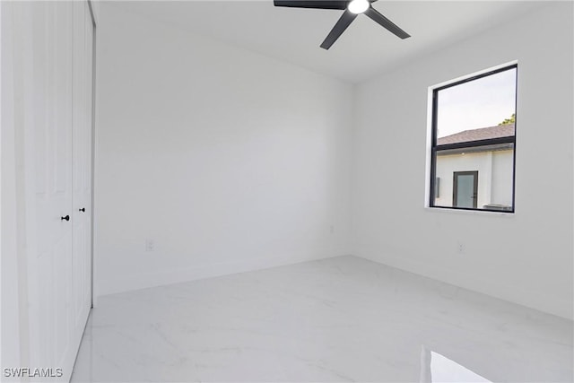 empty room with baseboards, marble finish floor, and ceiling fan