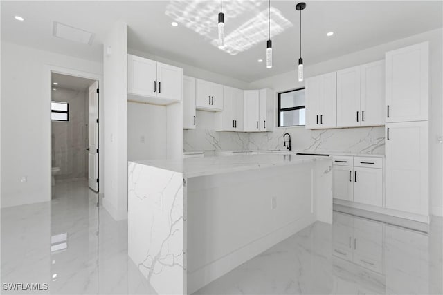 kitchen with decorative light fixtures, a center island, light stone counters, white cabinets, and marble finish floor