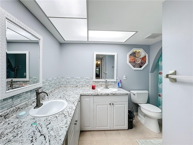 bathroom featuring vanity, tile patterned flooring, backsplash, and toilet