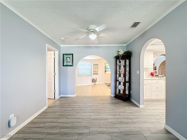hallway featuring visible vents, arched walkways, baseboards, and crown molding