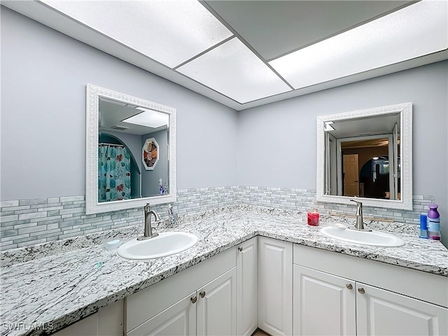 bathroom featuring a sink, tasteful backsplash, and double vanity