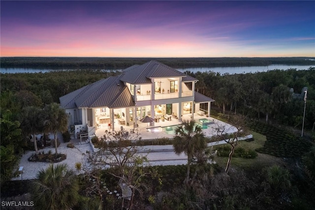 1247 Blue Hill Creek Dr, Marco Island, FL 34145 - back of house with a balcony, a patio area, metal roof, a pool with connected hot tub, and a water view