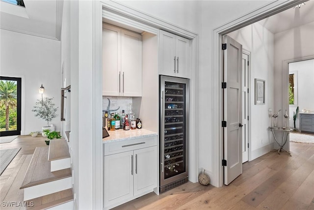 1247 Blue Hill Creek Dr, Marco Island, FL 34145 - indoor dry bar featuring beverage cooler, light wood-style flooring, decorative backsplash, and baseboards