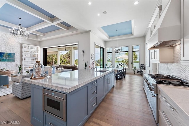 1247 Blue Hill Creek Dr, Marco Island, FL 34145 - kitchen featuring high end range, a chandelier, under cabinet range hood, a sink, and light wood-style flooring