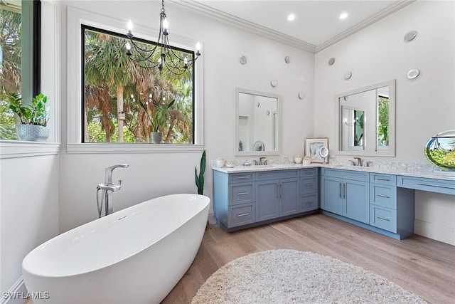 1247 Blue Hill Creek Dr, Marco Island, FL 34145 - bathroom featuring a freestanding bath, wood finished floors, crown molding, healthy amount of natural light, and double vanity