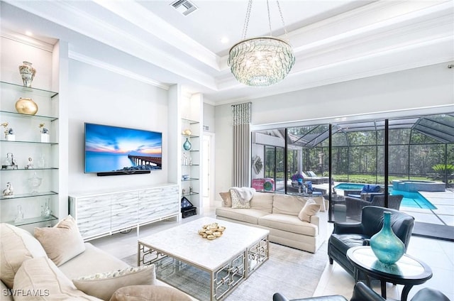 living area with visible vents, crown molding, built in features, a sunroom, and a notable chandelier