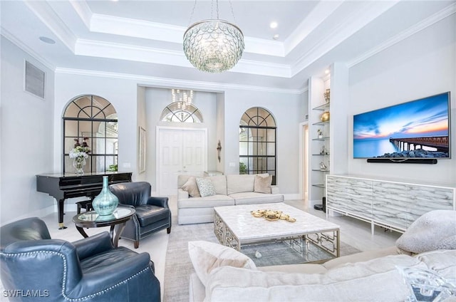 living area featuring crown molding, an inviting chandelier, built in shelves, a tray ceiling, and visible vents