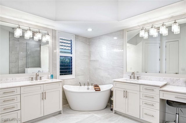 bathroom featuring a sink, a freestanding bath, two vanities, and tile walls
