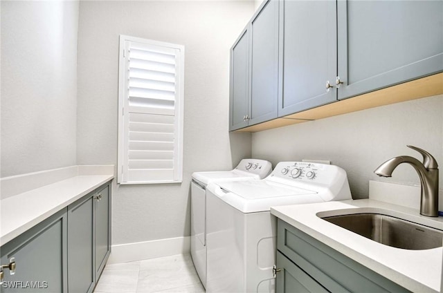 washroom featuring cabinet space, baseboards, washing machine and dryer, and a sink