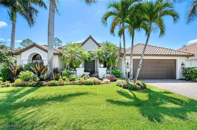 view of front of property featuring a tile roof, a front yard, a garage, decorative driveway, and stucco siding
