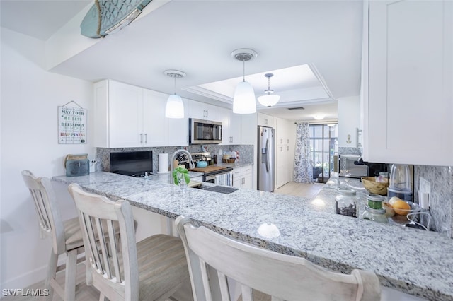 12130 Kelly Greens Blvd Unit 91, Fort Myers, FL 33908 - kitchen featuring stainless steel appliances, backsplash, white cabinetry, a tray ceiling, and light stone countertops