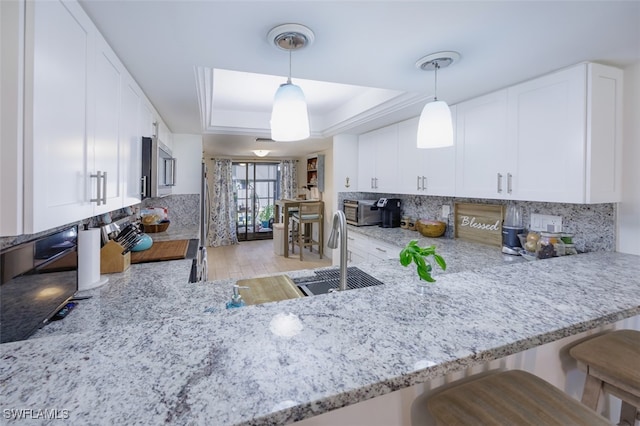 12130 Kelly Greens Blvd Unit 91, Fort Myers, FL 33908 - kitchen with a tray ceiling, tasteful backsplash, and light stone counters