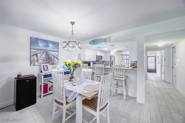 12130 Kelly Greens Blvd Unit 91, Fort Myers, FL 33908 - dining area with a notable chandelier, light wood-type flooring, and baseboards
