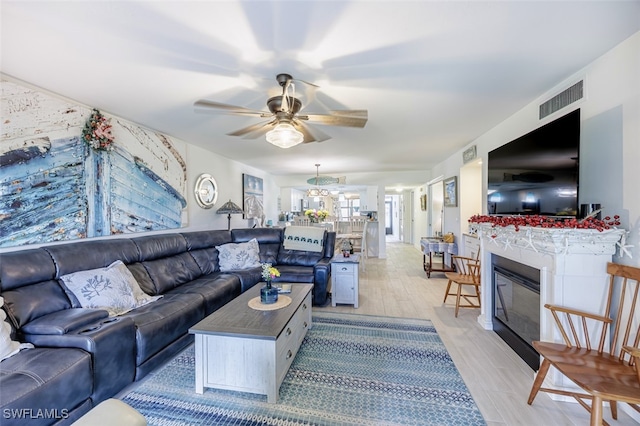 12130 Kelly Greens Blvd Unit 91, Fort Myers, FL 33908 - living area featuring light wood-style flooring, a glass covered fireplace, a ceiling fan, and visible vents
