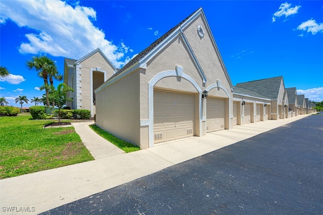 12130 Kelly Greens Blvd Unit 91, Fort Myers, FL 33908 - view of property exterior featuring a yard, stucco siding, and community garages