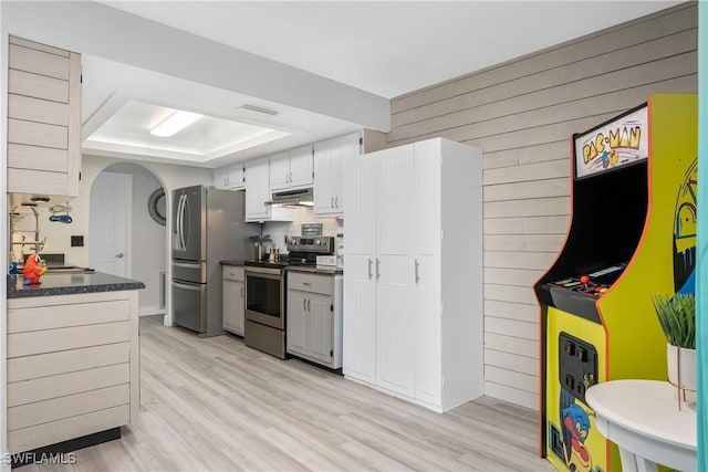 7666 Laurel Valley Rd, Fort Myers, FL 33967 - kitchen featuring stainless steel appliances, under cabinet range hood, dark countertops, wooden walls, and arched walkways