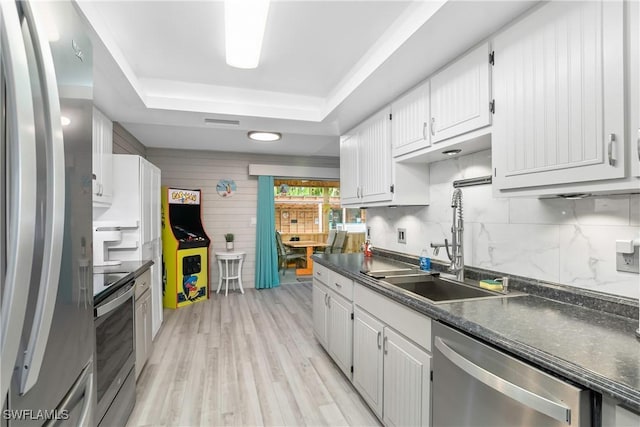 7666 Laurel Valley Rd, Fort Myers, FL 33967 - kitchen featuring stainless steel appliances, a tray ceiling, dark countertops, a sink, and tasteful backsplash