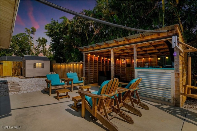 7666 Laurel Valley Rd, Fort Myers, FL 33967 - patio terrace at dusk featuring a storage shed, an outdoor structure, and fence