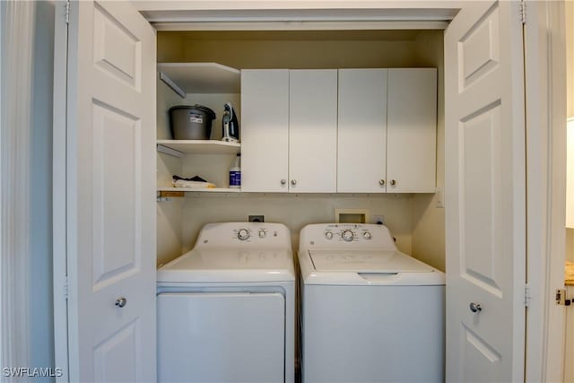 clothes washing area featuring cabinet space and washer and dryer