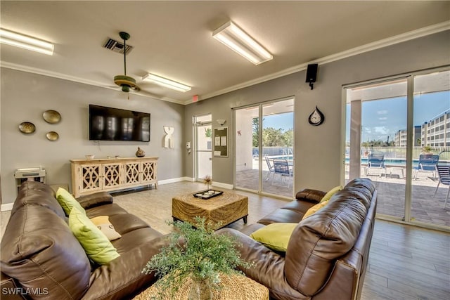 living room with wood finished floors, visible vents, crown molding, a ceiling fan, and baseboards
