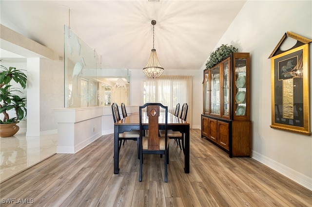 dining room featuring baseboards, a notable chandelier, and light wood-style flooring