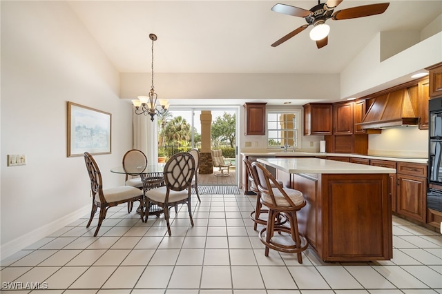 kitchen with a kitchen island, hanging light fixtures, light countertops, premium range hood, and ceiling fan with notable chandelier