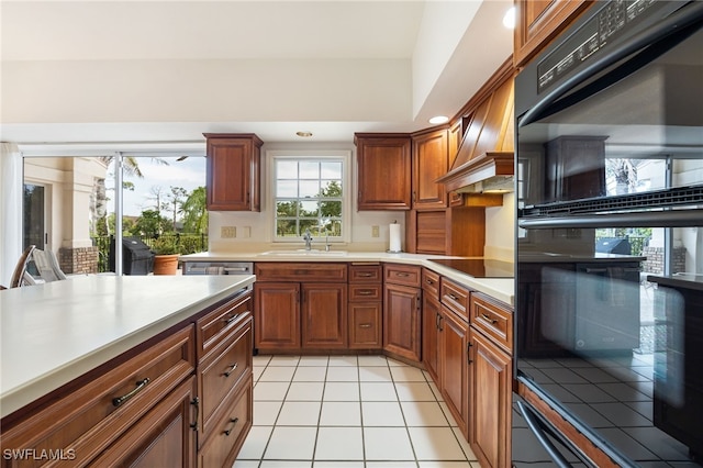 kitchen featuring a sink, light countertops, light tile patterned floors, custom range hood, and black appliances